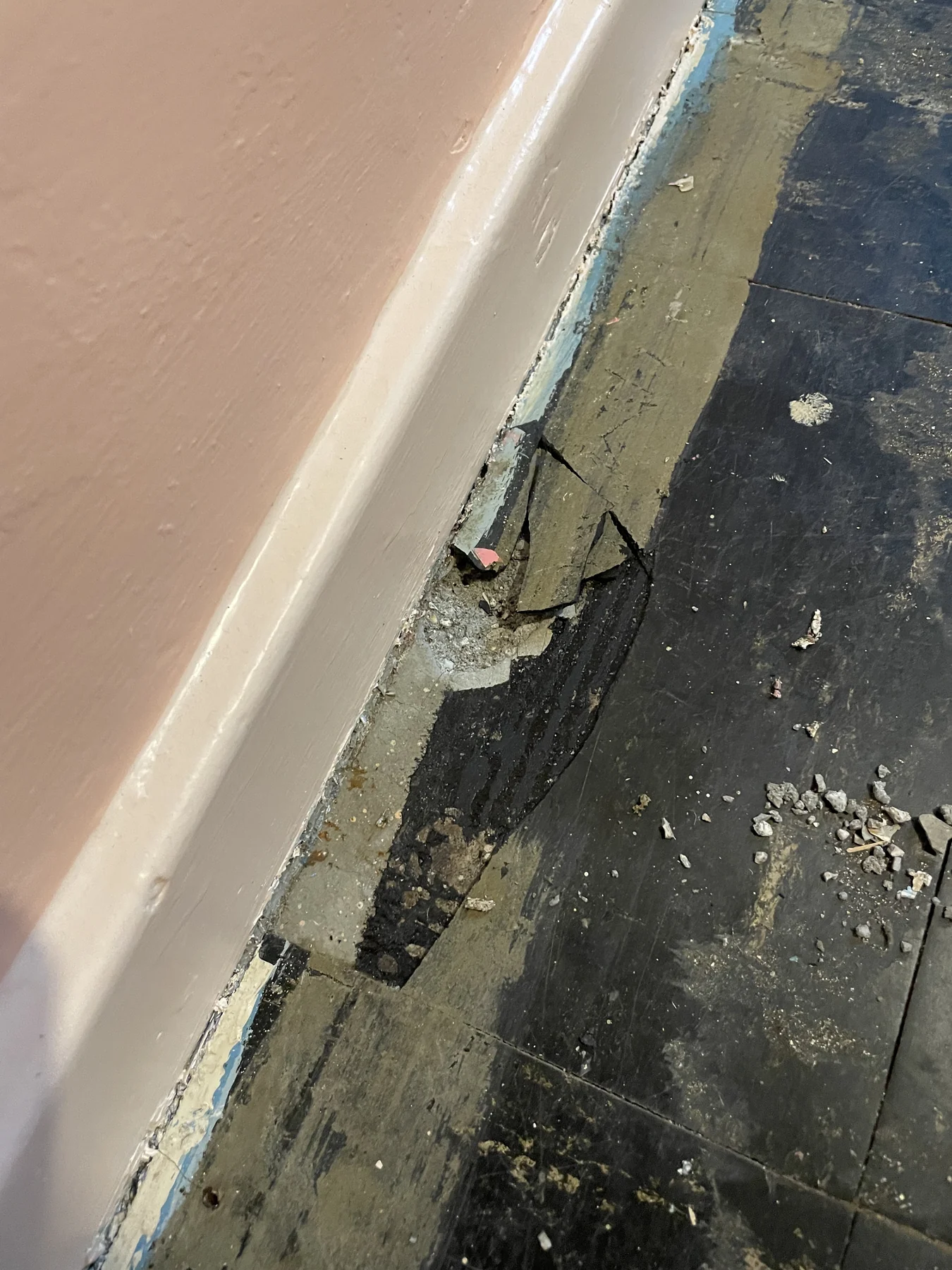 Old asbestos floor tiles and black bitumen adhesive before removal in a Richmond property