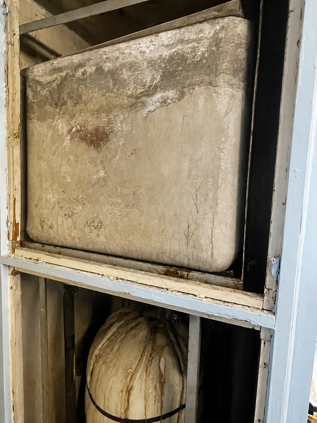 Close-up of an asbestos water tank inside a cupboard in London