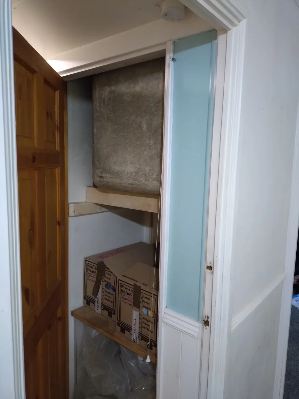 Large asbestos water tank built into a cupboard in a London home